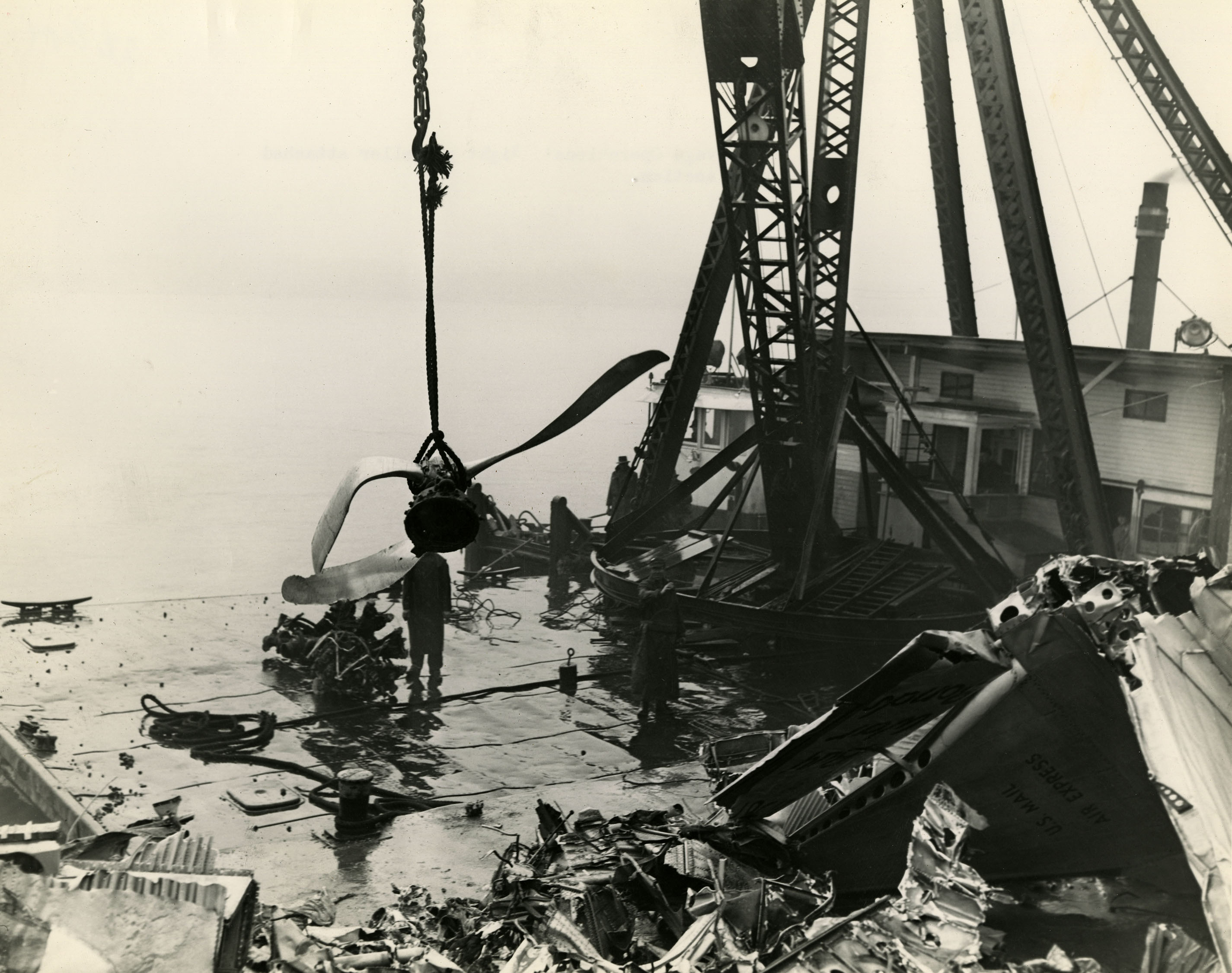 a crane lowering a twisted propeller onto a barge
